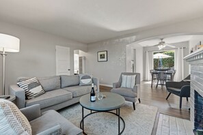 A living room with a sofa, armchair, round coffee table, and a fireplace. - 5*/One Parking Spot/5 Walk To Beach/Open July 18 - 23rd (La Jolla)