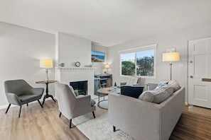 A living room with a fireplace, a sofa, a chair, a coffee table, and a TV. - 5*/One Parking Spot/5 Walk To Beach/Open July 18 - 23rd (La Jolla)