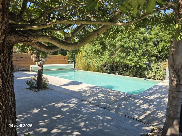 Une piscine entourée d’arbres et dotée d’une terrasse en bois.