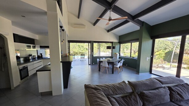 Una cucina moderna con zona pranzo, ampie finestre e ventilatore a soffitto.