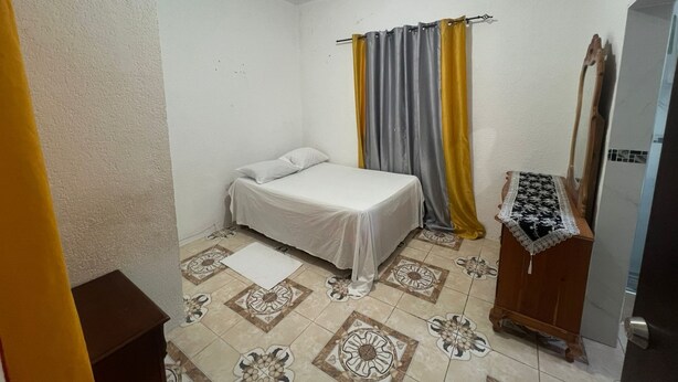 A small, clean room with a bed, a wooden dresser, and a mirror. - Peaceful 1-bedroom apartment with AC in charming Ocho Rios (Ocho Rios)