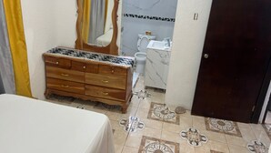A bathroom with a wooden vanity, a mirror, a toilet, and a sink. - Peaceful 1-bedroom apartment with AC in charming Ocho Rios (Ocho Rios)