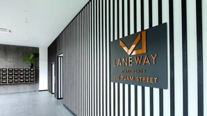 A modern hallway with a vertical striped wall, a sign for Laneway Apartments at 150 Tuam Street, and a plant on a shelf. - 2 Bedrooms Apprtmt Plus Underground Parking in CBD (Christchurch)