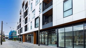 A modern multi-story building with large glass windows, a flat facade, and a pedestrian walkway. - 2 Bedrooms Apprtmt Plus Underground Parking in CBD (Christchurch)
