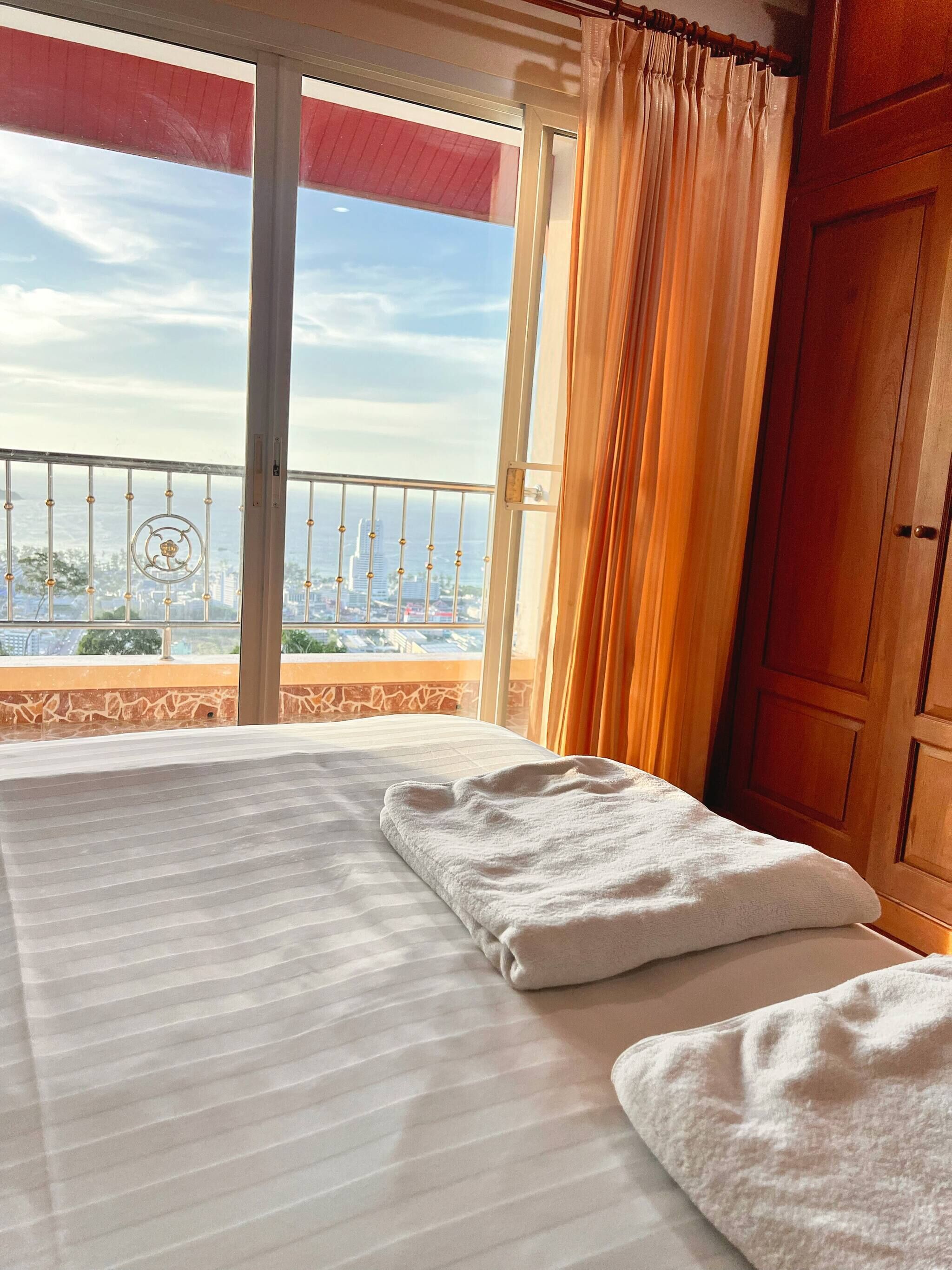 Une chambre d’hôtel avec un lit, une vue sur le paysage urbain depuis un balcon et une porte en bois.