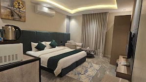 A modern hotel room with a large bed, a desk, a television, and an air conditioning unit. - dormira serviced apartments (Riyadh)