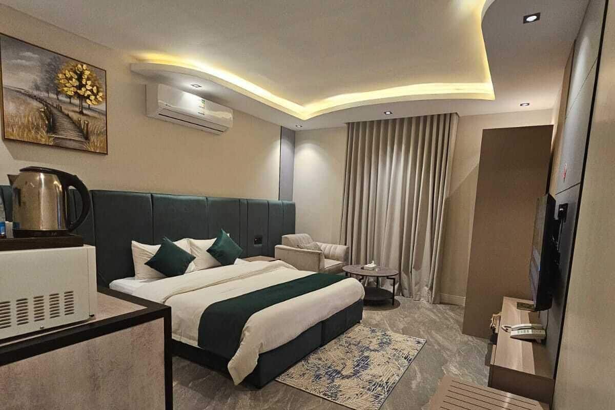 Una habitación de hotel moderna con una cama grande, un escritorio, un televisor y un equipo de aire acondicionado.