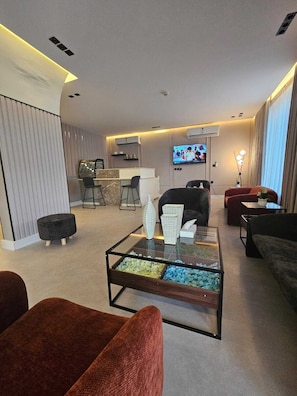 A modern living room with a glass coffee table, a TV, and comfortable seating.