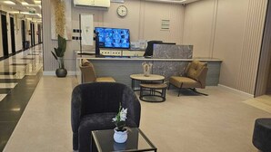 A modern lobby with a reception desk, seating area, and a large flat-screen TV. - dormira serviced apartments (Riyadh)