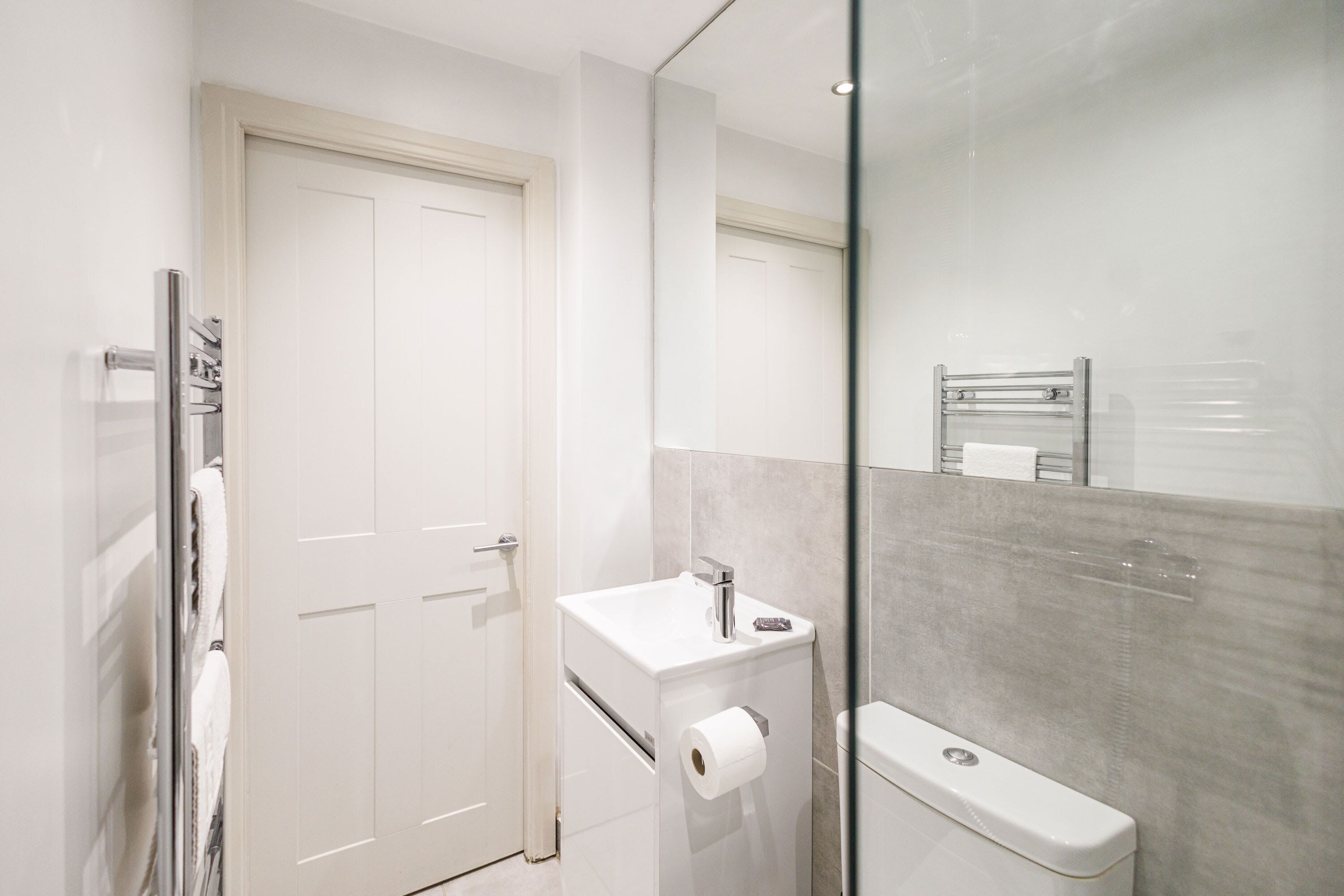 A modern bathroom with a toilet, a sink, and a glass shower enclosure.