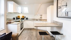 Una cocina moderna con armarios blancos, encimera de madera y un reloj de pared grande.