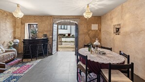 Ein Essbereich mit Tisch für zwei, eine Bar mit Barhocker und ein Blick durch einen Bogen ins Freie.