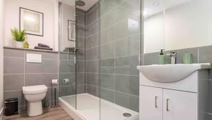 A modern bathroom with a glass-enclosed shower, a white toilet, and a white sink with a curved basin. - Central 1-bed Apartment With Free Parking & Wifi (Leicester)