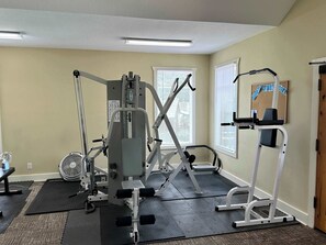 A gym with various exercise equipment, including a bench press, a leg press, and a cable machine.