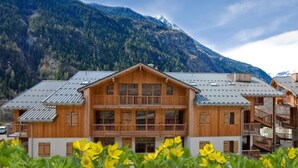 A wooden chalet with multiple balconies, set against a mountainous backdrop. - Apartment Near Centre of Orelle (Orelle)