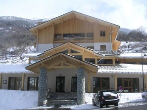 A two-story wooden building with a stone entrance and a balcony on the upper floor. - Apartment Near Centre of Orelle (Orelle)