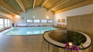 An indoor swimming pool with a wooden ceiling, a hot tub, and lounge chairs. - Apartment Near Centre of Orelle (Orelle)