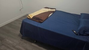 Une chambre avec un lit, un téléviseur fixé au mur et un luminaire au plafond.