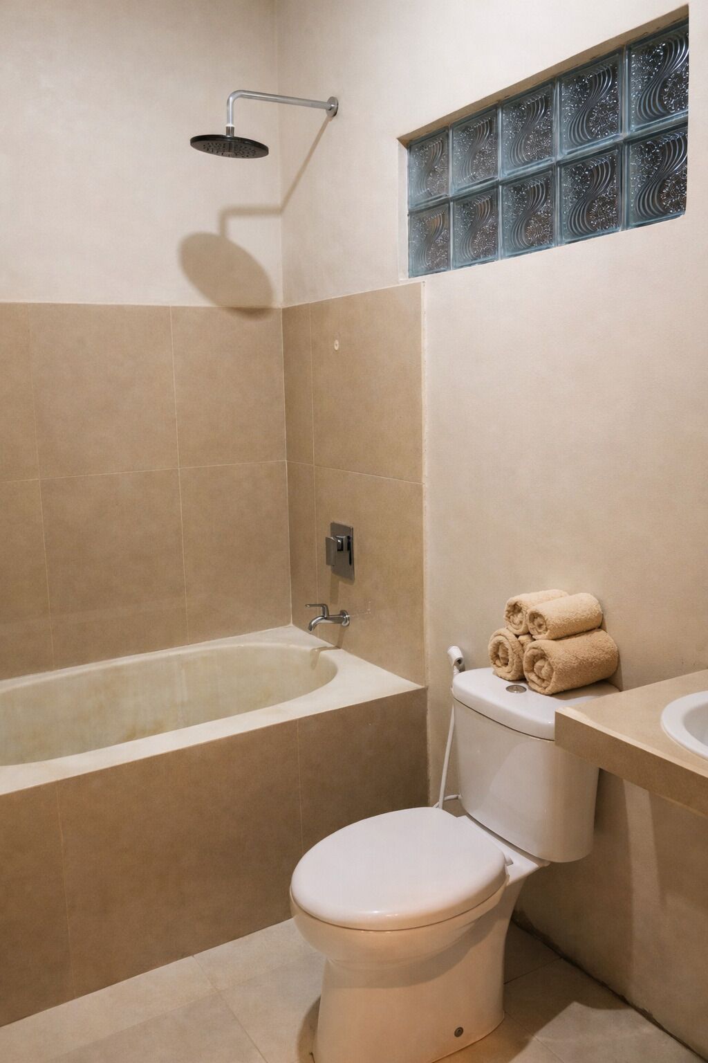 A bathroom with a bathtub, toilet, and a window with decorative glass.