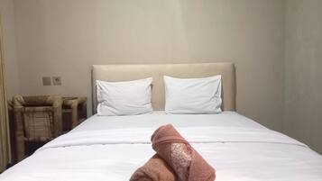 Habitación de hotel con cama, dos almohadas, cabecera y una silla.