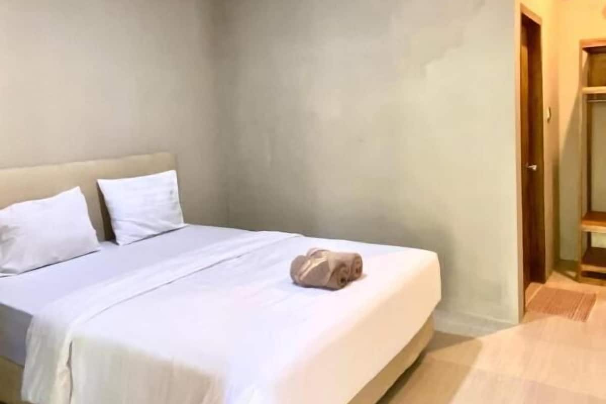 Habitación de hotel con una cama grande, suelo de madera y una puerta a la derecha.
