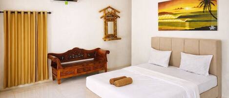 A bedroom with a bed, a wooden bench, a wall-mounted mirror, and a painting of a sunset.