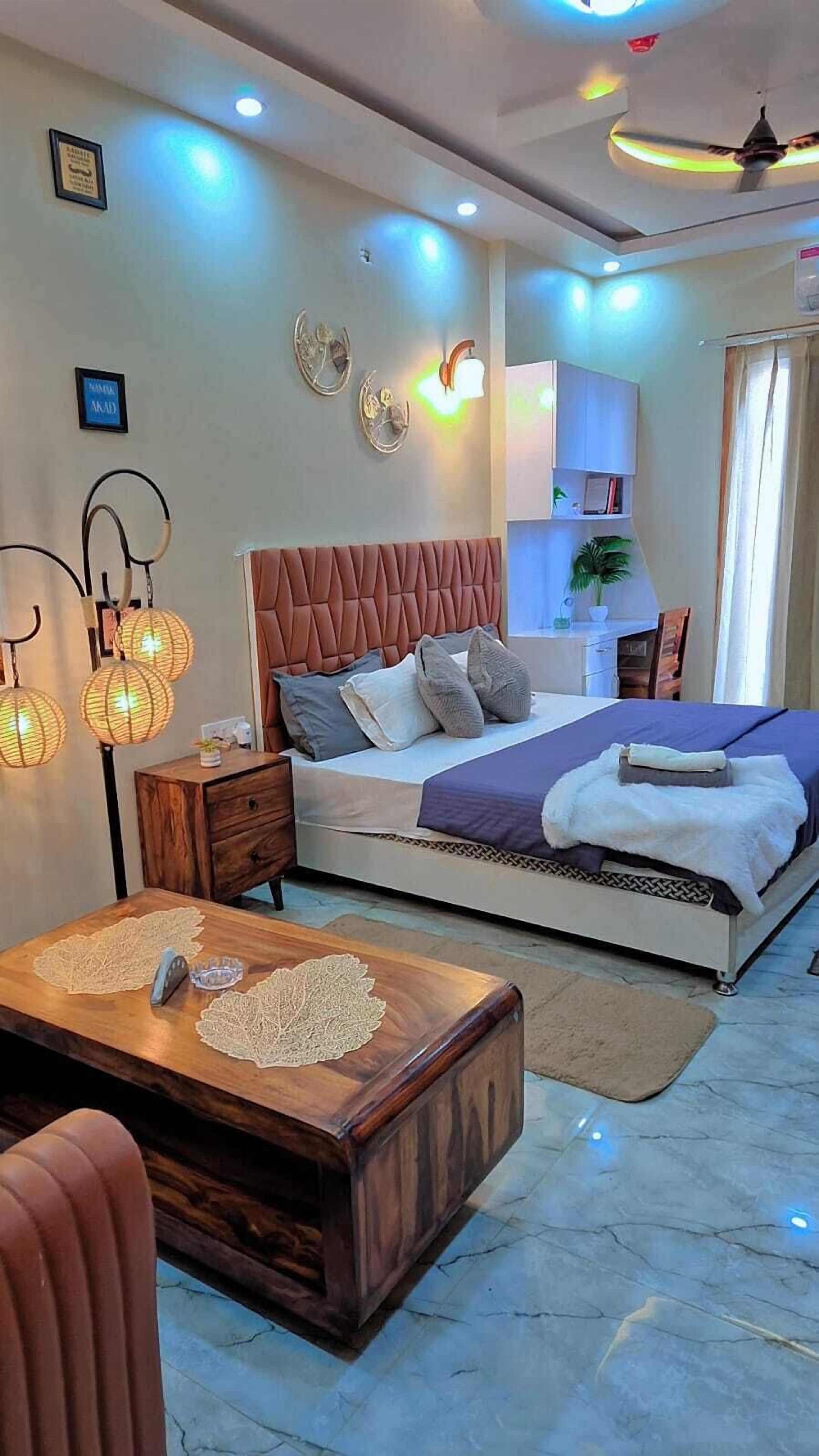 Une chambre à coucher moderne, avec un lit, des tables de chevet, une table basse en bois et des appliques murales décoratives.