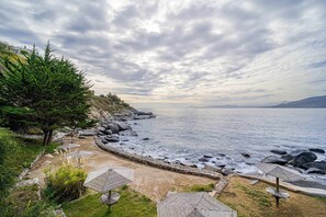 Una playa costera con sombrillas y un litoral rocoso.