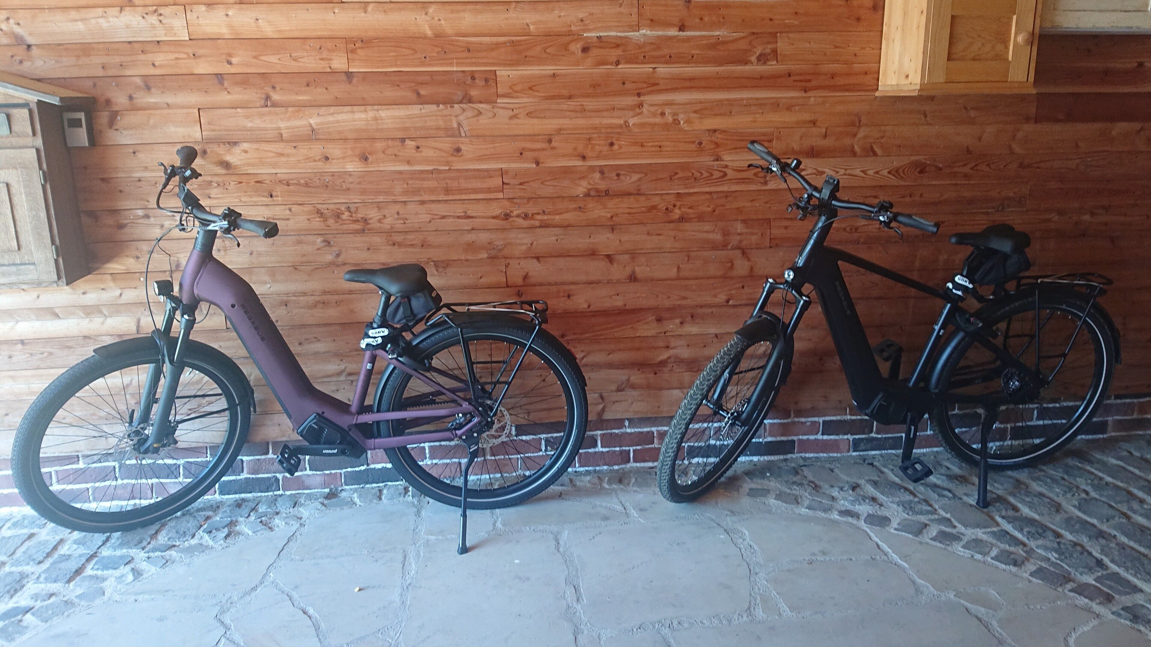 Duas bicicletas encostadas a uma parede de madeira.