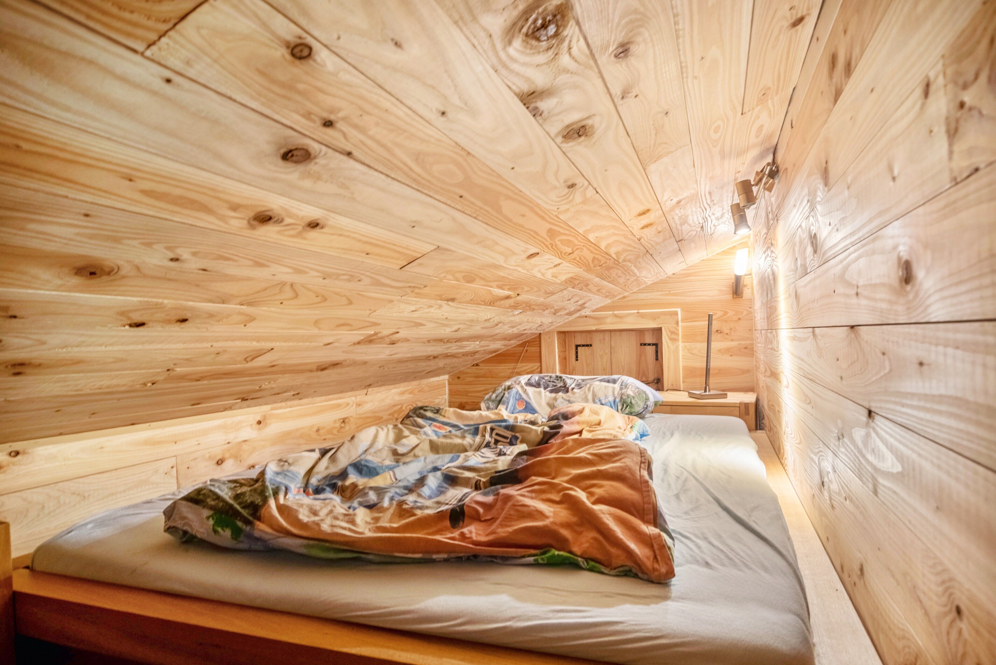 Eine Holzhütte mit Schlafzimmer im Loft-Stil, inklusive eines Etagenbettes, Holzboden und einem kleinen Fenster.