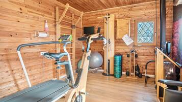A wooden cabin with a treadmill, exercise ball, and weights.
