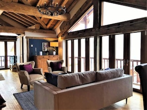 A cozy living room with a sofa, armchairs, and a wooden ceiling. - Chalet Chêne - Panoramic Isere Valley Views (Sainte-Foy-Tarentaise)