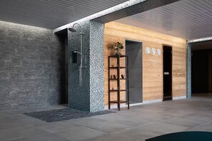 A modern lobby with a stone shower enclosure, a wooden reception desk, and a tiled floor. - Chalet Chêne - Panoramic Isere Valley Views (Sainte-Foy-Tarentaise)