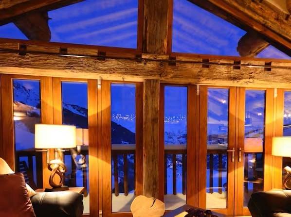 A cozy room with large windows, wooden beams, and a view of a snowy landscape. - Chalet Chêne - Panoramic Isere Valley Views (Sainte-Foy-Tarentaise)