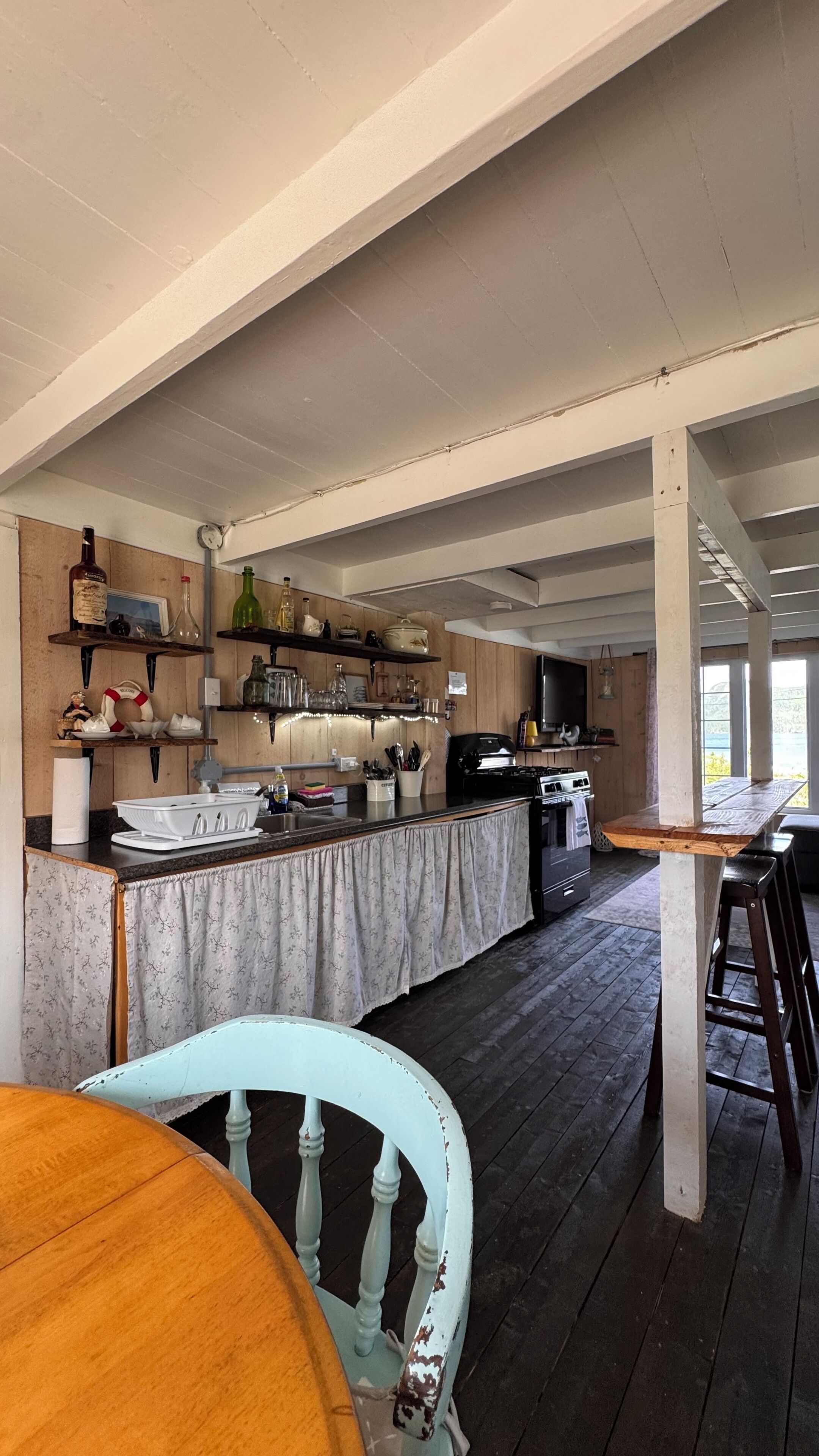 A spacious kitchen with wooden beams, a long counter, and a dining area with a wooden table and chairs.