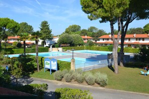 A residential area with a swimming pool, trees, and houses with red roofs. - Cozy Apartment With Shared Pool (San Michele al Tagliamento)