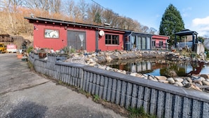 Un bâtiment rouge avec un étang, un mur de pierre et une structure métallique.