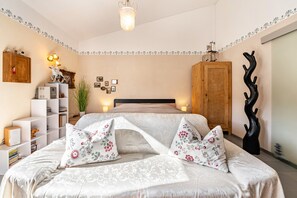 Ein Schlafzimmer mit Bett, Nachttischen, einem Kleiderschrank, einer Wanddekoration und einer Pendelleuchte.