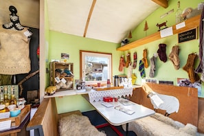 Ein gemütliches Zimmer mit einem rustikalen Holztisch, Regalen mit verschiedenen Gegenständen und einem Fenster mit Blick.