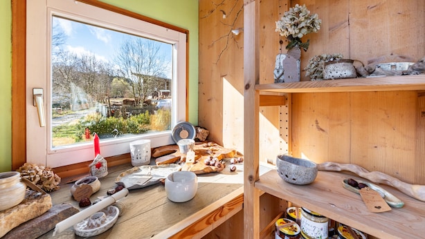 Une cuisine rustique avec des étagères en bois, une fenêtre donnant sur les arbres et divers ustensiles de cuisine.