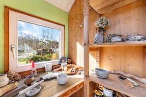 Eine rustikale Küche mit Holzböden, einem Fenster mit Blick auf Bäume und verschiedenen Küchenutensilien.