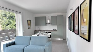 Ein modernes Wohnzimmer mit einem hellblauen Sofa, einem Esstisch für vier Personen und einer Küche im Hintergrund.