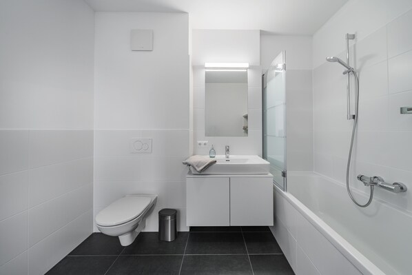 Une salle de bain moderne équipée de toilettes, d’un lavabo et d’une douche.
