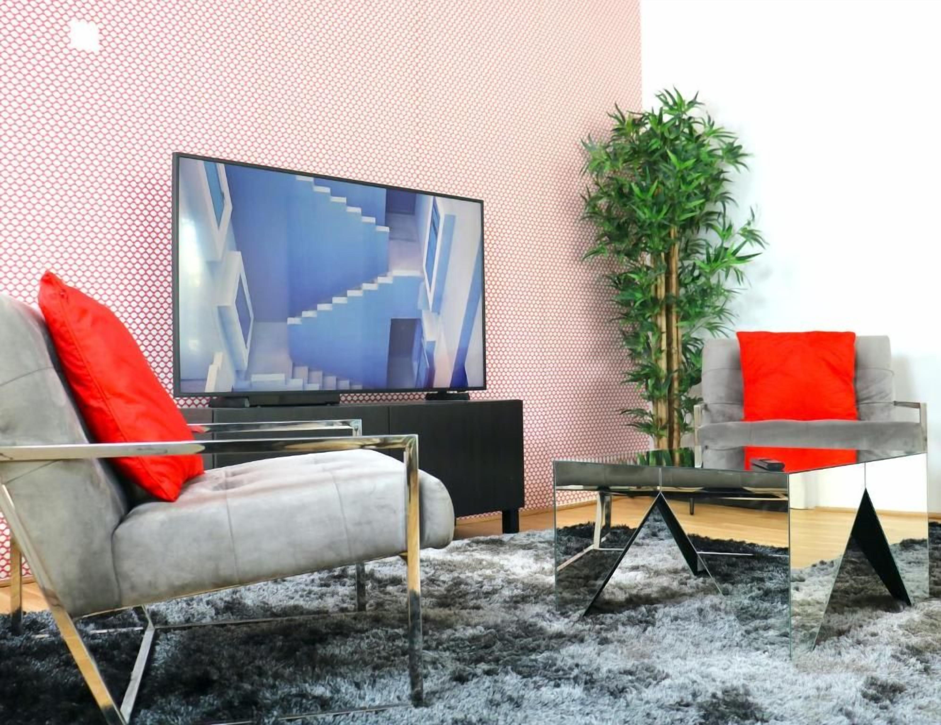 A modern living room with a sofa, a television, a coffee table, and a plant.