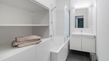 A modern bathroom with a shower, a sink, and a mirror.
