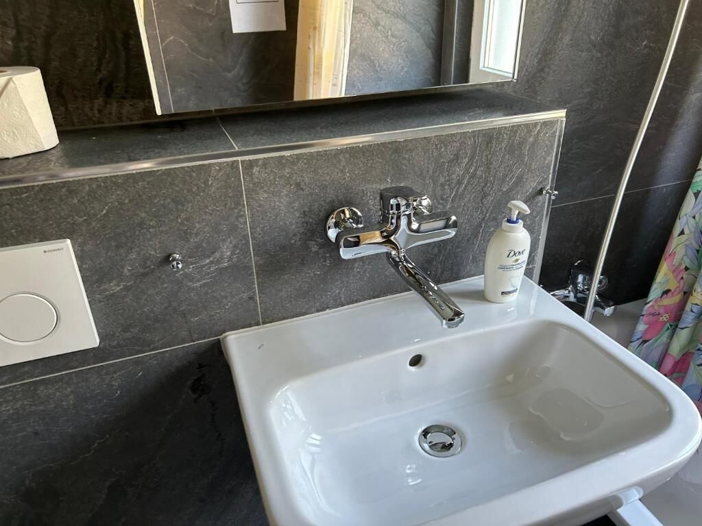 Une salle de bain avec un lavabo blanc, un miroir et un distributeur de serviettes.