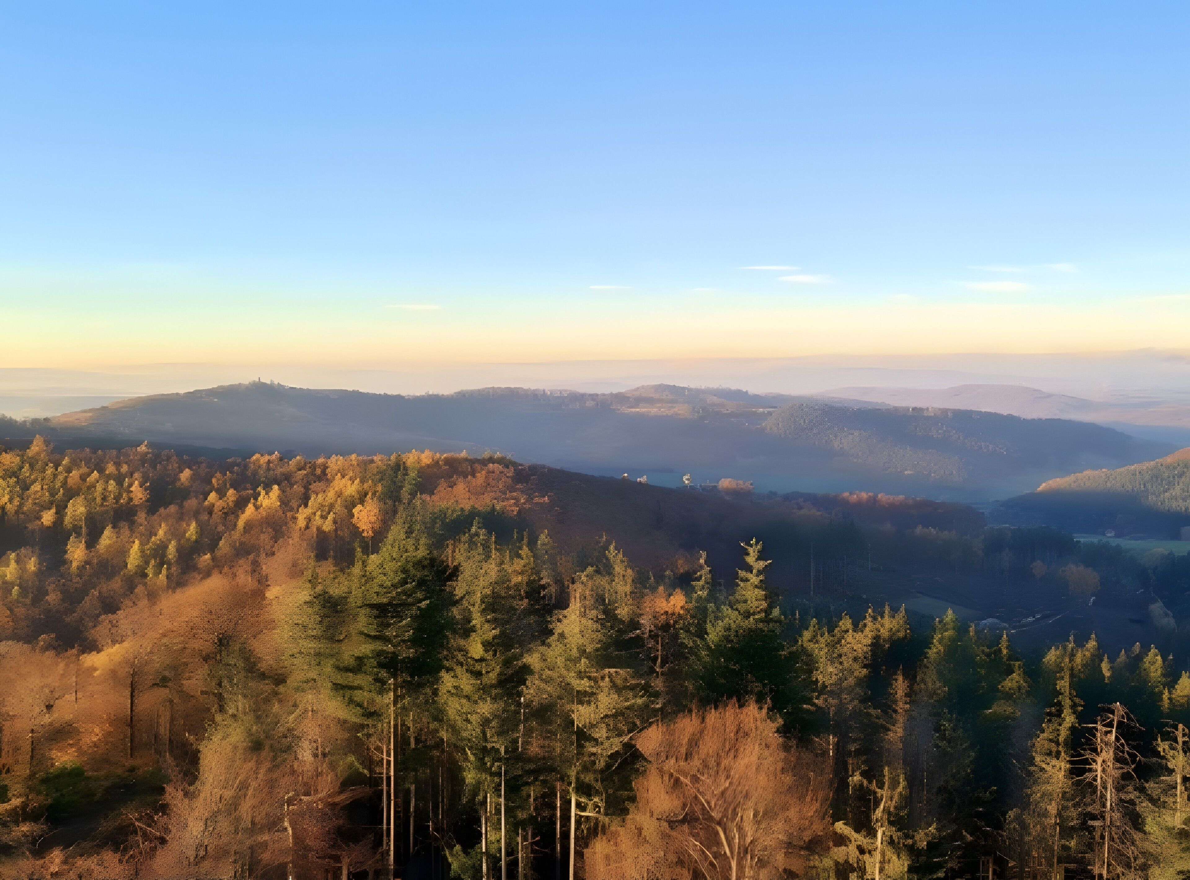 Vista panorámica de un paisaje montañoso con densos bosques y cielo despejado.