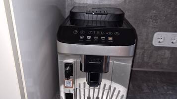 Una cafetera con pantalla digital, depósito de agua y bandeja para líquidos.