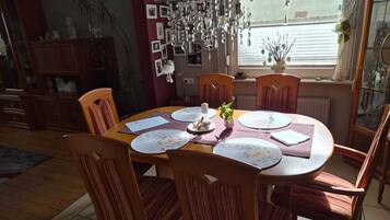 Un coin repas avec une table ronde, des chaises et un élément décoratif suspendu.