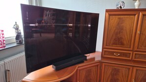 A flat-screen TV on a wooden stand, a cabinet with drawers, and a radiator.